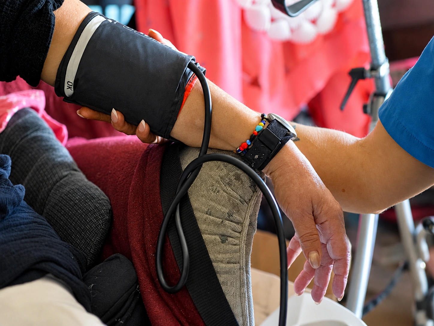 Pflegekraft legt einer Patientin die Manschette zur Blutdruckmessung an