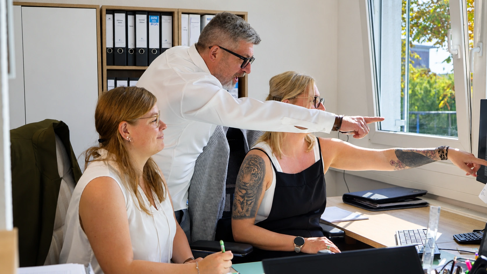 Büroteam der Pflege Intensiv GmbH bespricht an den Arbeitsplätzen die Einsatzplanung am Bildschirm